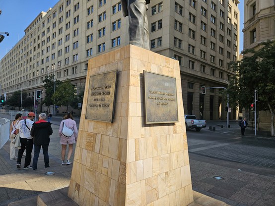 Pedestal de la estatua de Pedro Aguirre Cerda en el centro de Santiago, mostrando dos de las 4 placas de cobre escritas con tipografía Comic Sans.