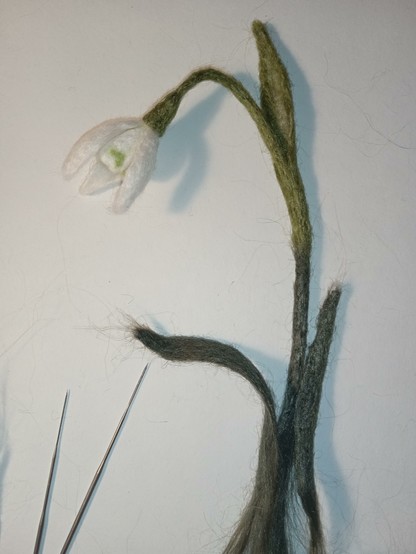 On a white background lies a snowdrop made of nettle using needle felting. This will be a bookmark in the form of a plant. There are two special felting needles lying nearby.
Thank you for your attention!