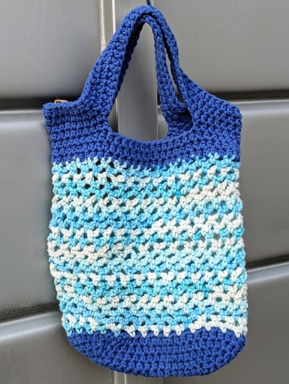 A crochet market bag in white and shades of blue.