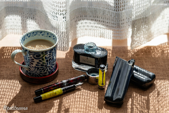 a cup of coffee, bottle of ink (Deep sea green), and Aurora's fountain pens