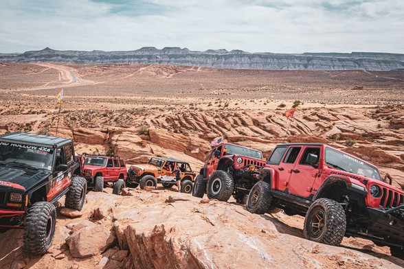 A bunch of jeeps parked on a steep, red-rock "hill".