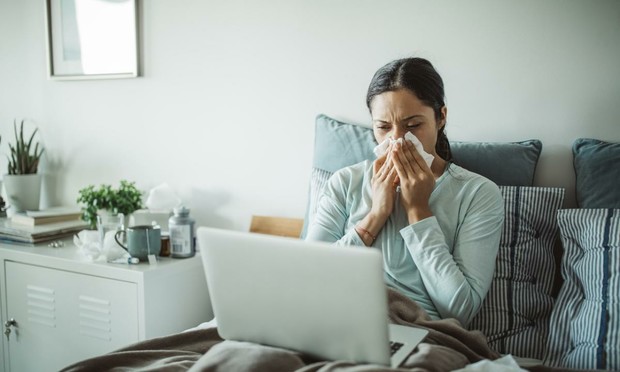 Una mujer con gripe, en cama con el ordenador del trabajo. (SVETLANA DAMJANAC)