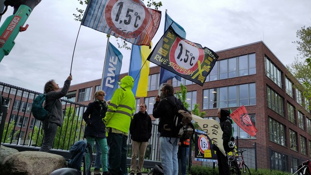 Wehende Fahnen und Demonstrant*innen vor einem Bürogebäude