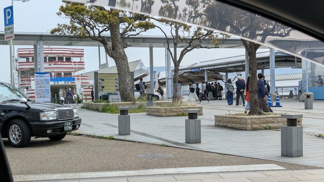 A picture of Takamatsu port taken from a car. There are ferries and people mostly.