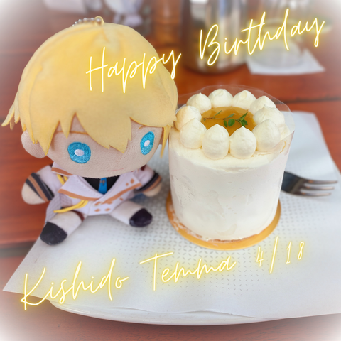 Kishido Temma nui/plushie (blond hair, blue eyes with a white knight unfirom with yellow and black accents) next to a small white cake. The center of the cake is yellow/brown. There's "Happy Birthday Kishido Temma" text.