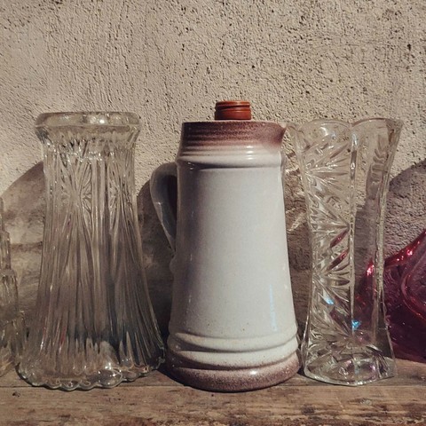 Vessels made of clay and glass in front of a wall.