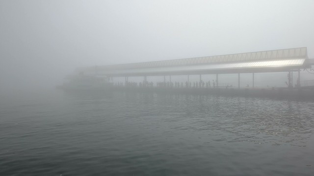 A pier at Takamatsu Port, except that there is heavy fog. I'm a few dozen meters away and it's barely visible. There are some people waiting in line and the ferry to Oshima, but it's not running.