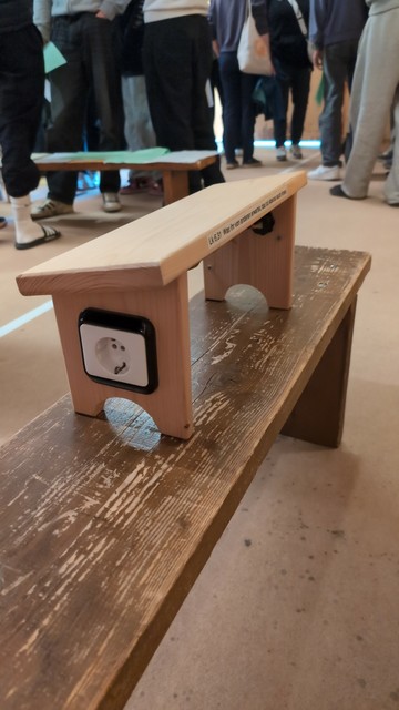 Prayer Bench mit seitlich angebrachter Steckdose. Nicht sichtbar sind die unter der Sitzfläche angebrachte Powerbank und die USB-Anschlüsse auf der anderen Seite.