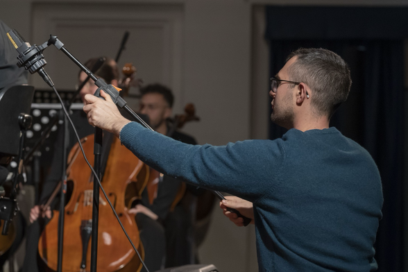 Nicola Monopoli regola l’asta di un microfono AKG C414, sullo sfondo l’orchestra.
