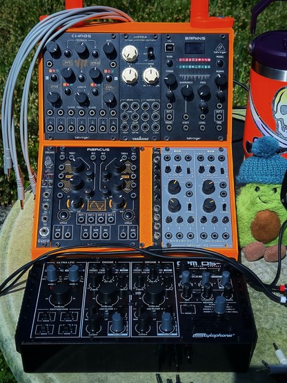 The drone operations unit… an orange 3D-printed Eurorack case packed with Behringer Chaos (random command), uniCYCLE (main oscillator), Brains (timbre modulator), and an Erica Synths Pico Drums for rhythmic anomalies. A 2HP Catsynth mixer (catsynth.de) discreetly hides in the shadows… silently routing signals like a cloaked Romulan operative. The Behringer Abacus manages time-based functions, while the bottom-right corner hosts a Behringer Dual LFO… because in this quadrant, you can never have enough LFOs. Below, the Stylophone CPM-DS2 drone synth hums with alien resonance… equipped with three oscillators, one of which serves as the Ultra LFO. It’s ready to open a wormhole through drone-space. AvocaJoe monitors from the flank… all systems stable. Slight phase drift detected… realignment possible.