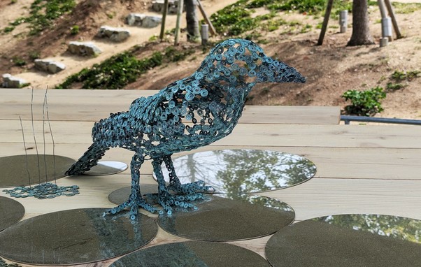 A statue of a crow (roughly life-size) made of metal strings.