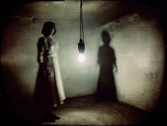 Chambre d’Ombre.
Scène figée d’un film d’horreur des années 70, une silhouette floue sous une ampoule nue, projetant une ombre qui semble vivante.
Still frame from a 1970s horror film, a blurry figure under a bare bulb, casting a shadow that seems to have a life of its own.