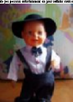 A low quality, blurry photo of an Action Singer (a small doll with a baby-like face wearing a white button-up shirt, a black bow tie, and denim overalls with a black hat on, standing on a black plastic base). There is a caption above the image that says "do you possess entertainment on your cellular device" (meant to be an overly verbose form of "you got games on your phone"), though the caption is so squashed you can barely read it due to the low pixel density.