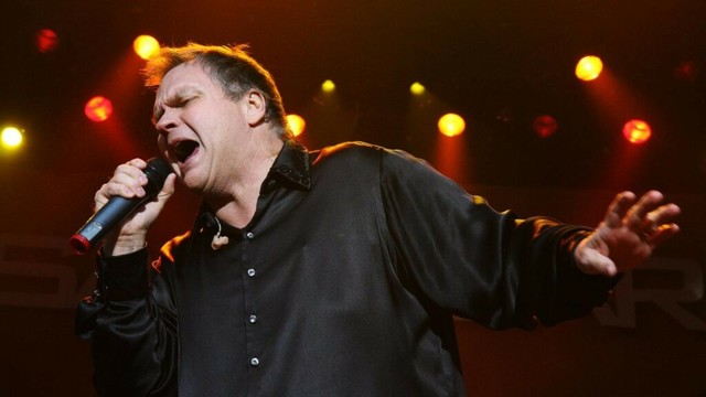 Ein Mann steht mit ausgebreiteten Armen auf einer Bühne und singt. In der rechten Hand hält er ein Mikrofon. Es ist der US-Rockmusiker Meat Loaf.