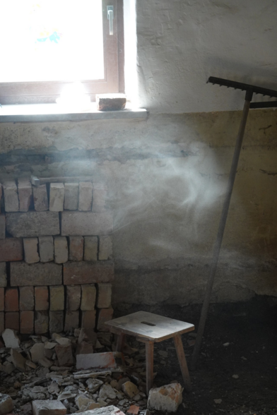 Staub über einem Schemel, vor aufgestapelten Klinkersteinen