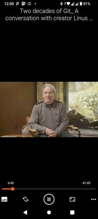 The screencap showcases a VLC video player interface on an Android with a video titled "Two decades of Git: A conversation with creator Linus..." The video is currently at 4:40 out of a total duration of 41:49. The video features a man Linus Torvalds sitting in a chair, wearing a gray long-sleeve shirt with a small logo on the left side, and dark pants. He is seated in front of a large window with a view of greenery outside. There are two glasses of water on a small table to his left. The background includes a wooden wall and a large window, suggesting an indoor setting with natural light. The video player interface includes standard controls such as play, pause, and volume adjustment, along with a progress bar indicating the current playback position.

 Ovis2-8B

🌱 Energy used: 0.187 Wh