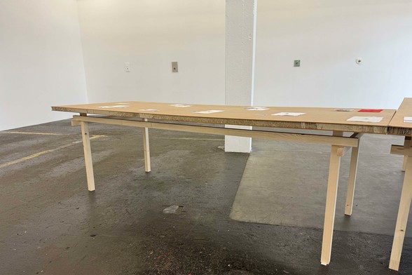 Wide photograph of a minimalist table in a gallery space.