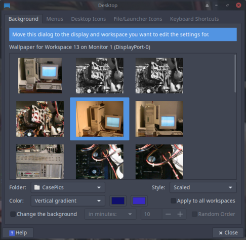 The image shows a desktop settings dialog box for selecting a wallpaper. The title at the top reads "Desktop" and includes tabs for "Background," "Menus," "Desktop Icons," "File/Launcher Icons," and "Keyboard Shortcuts." The main section of the dialog box is titled "Wallpaper for Workspace 13 on Monitor 1 (DisplayPort-0)" and features a grid of nine wallpaper images. The selected wallpaper is an image of an old computer setup with a monitor and keyboard. Below the grid, there are options for the folder ("CasePics"), style ("Scaled"), and color ("Vertical gradient"). Additional settings include a checkbox to "Change the background" every 10 minutes, a "Random Order" option, and a "Help" button. The dialog box also has a "Close" button in the top right corner.