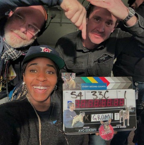 Ayo Edebiri with the clapperboard for the series "TheBear" season , scene 1. Her name is on the clapperboard. Two of her co-workes are in the pic as well and point to Ayo as the boss.