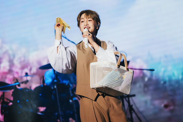 Onew throws paper planes to the audience