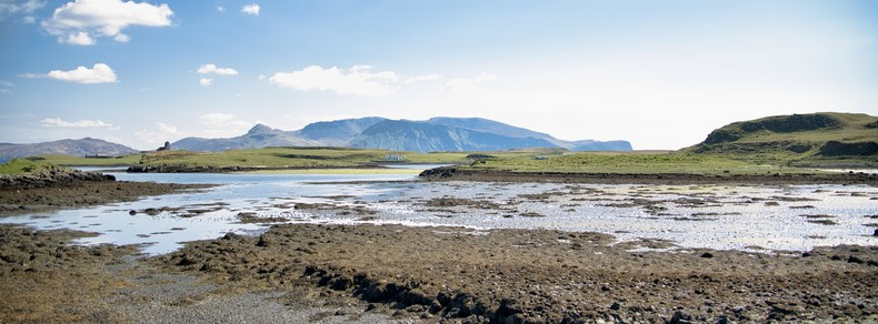 An image of an estuary with mountains behind and a blue sky above. Canna, Scotland