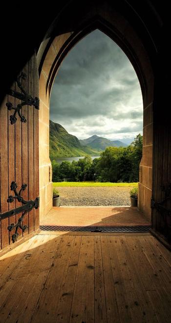 Medieval-looking doorway with picturesque mountain landscape seen through it
