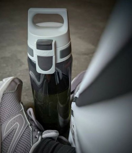 Meine übereinander geschlagenen Beine in Sportklamotten. Davor meine Trinkflasche.