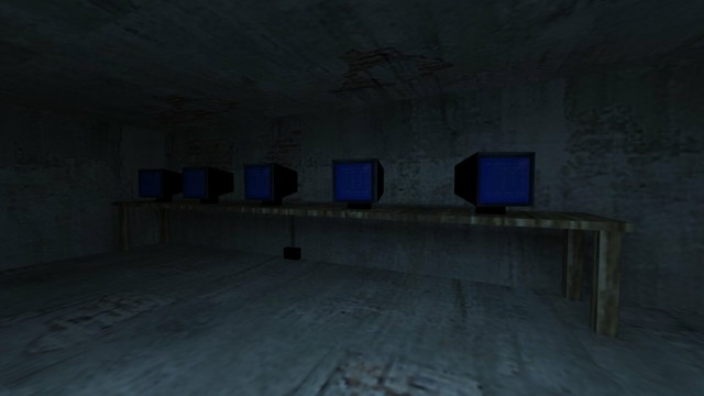 In this picture you can see the underground of the house. Actually the cellar, which merges into the Sewer. You can see an unlit room. On the wall is a very long wooden desk. There are five black CRT monitors on these. These show a blue background with white lettering on it. Under the desk, a small black box can be seen in the middle, where a cable leads up to the monitors. It's probably a socket. This is on the map cs_militia in the game Counter-Strike 1.6.
