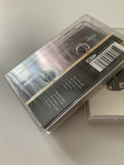 A close-up of one compact cassette (tape) that shows that the plastic wrap around its case is still unopened