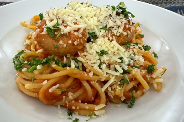 Homemade spaghetti and meatballs topped with loads of parmesan cheese and freshly chopped parsley.