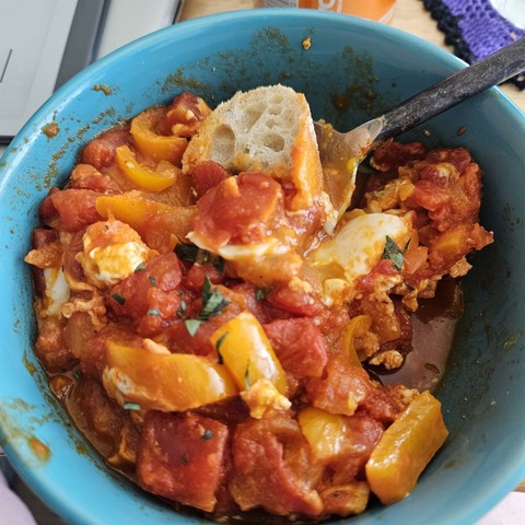 shakshuka in a teal bowl with a bit of bread