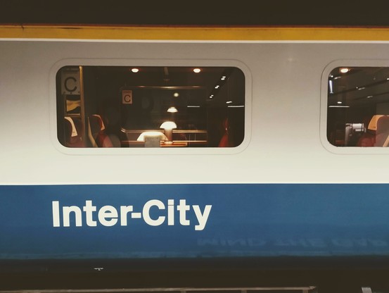 Side image of an old-style UK Inter-City train in yellow, white, and blue livery.