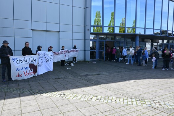 Eine Gruppe von Aktivis steht vor dem Eingang der Halle Münsterland und hält Banner mit "Menschen Lachen - Pferde leiden" daneben gehen die Zuschauer in die Pferdeshow "Cavalluna"