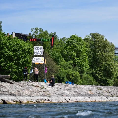 Ein Bohrturm direkt an der Isar (Reichenbachbrücke) mit der Message "Exit Fossils", "Koa Gas" und "Stoppt die Gasbohrungen" sowie Flaggen mit dem Logo von Extinction Rebellion. Hiermit soll auf die geplanten Gasbohrungen in Reichling am Ammersee aufmerksam gemacht werden.