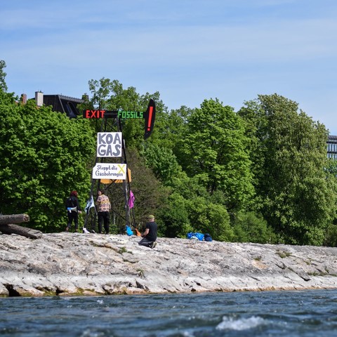 Ein Bohrturm direkt an der Isar (Reichenbachbrücke) mit der Message "Exit Fossils", "Koa Gas" und "Stoppt die Gasbohrungen" sowie Flaggen mit dem Logo von Extinction Rebellion. Hiermit soll auf die geplanten Gasbohrungen in Reichling am Ammersee aufmerksam gemacht werden.