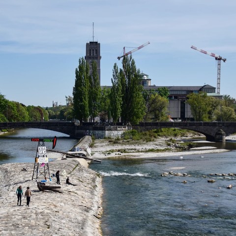 Ein Bohrturm direkt an der Isar (Reichenbachbrücke) mit der Message "Exit Fossils", "Koa Gas" und "Stoppt die Gasbohrungen" sowie Flaggen mit dem Logo von Extinction Rebellion. Hiermit soll auf die geplanten Gasbohrungen in Reichling am Ammersee aufmerksam gemacht werden.