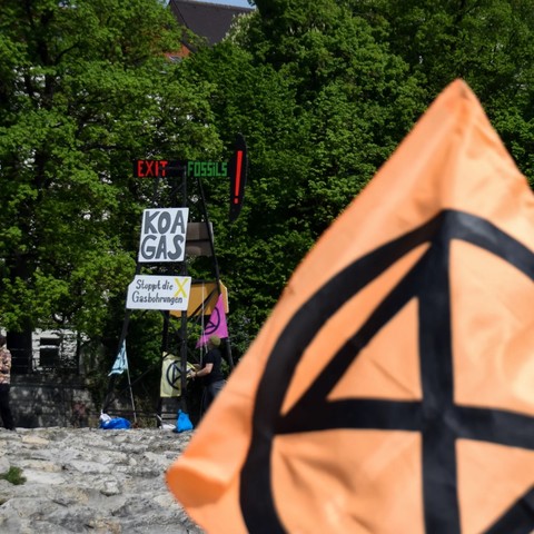 Ein Bohrturm direkt an der Isar (Reichenbachbrücke) mit der Message "Exit Fossils", "Koa Gas" und "Stoppt die Gasbohrungen" sowie Flaggen mit dem Logo von Extinction Rebellion. Hiermit soll auf die geplanten Gasbohrungen in Reichling am Ammersee aufmerksam gemacht werden.