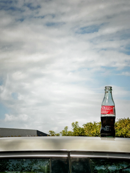 A bottle of coke on top of the car roof