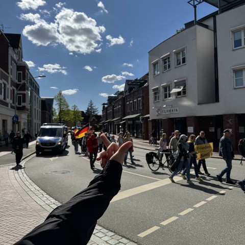 Ein Mensch hält einen Mittelfinger in Richtung der rechten Demo