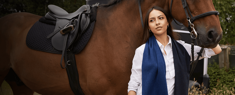Model wearing scarf with horse in background.
