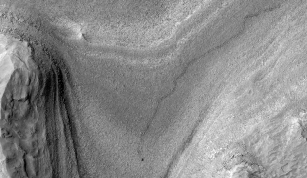 Il rover Curiosity della NASA appare come una macchiolina scura in questa vista con contrasto migliorato catturata il 28 febbraio 2025 dalla fotocamera HiRISE a bordo del Mars Reconnaissance Orbiter della NASA. A seguire Curiosity sono le tracce del rover, che possono rimanere sulla superficie marziana per mesi prima di essere cancellate dal vento.