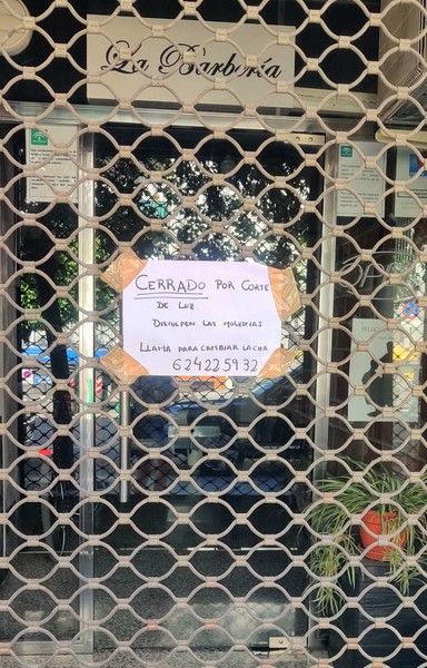 La Barbería, en Avenida de Dílar, con un cartel en la persiana cerrada indicando que cierra por el apagón.