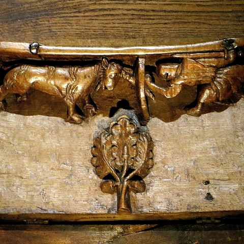 Woodcarving of a knight fighting an animal with a long horn.