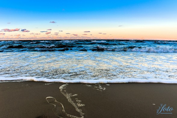 Ein herrlicher Sandstrand im Vordergrund, leichte Schaumkrone und dahinter Ostsee satt mit einem pastellfarbenen Sonnenuntergang 😍