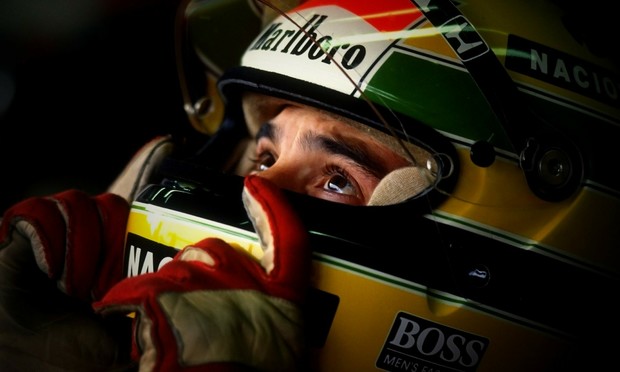 Ayrton Senna wearing his helmet with the colors of Brazil and the Marlboro logo. He looks up as if he is praying before a race.