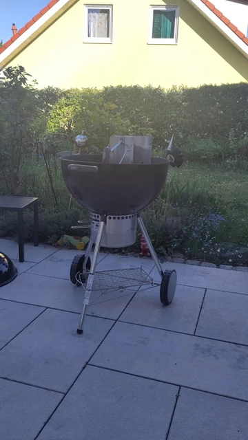 Ein Kugelgrill steht auf der Terrasse. Im Hintergrund sieht man Teile des Gartens.