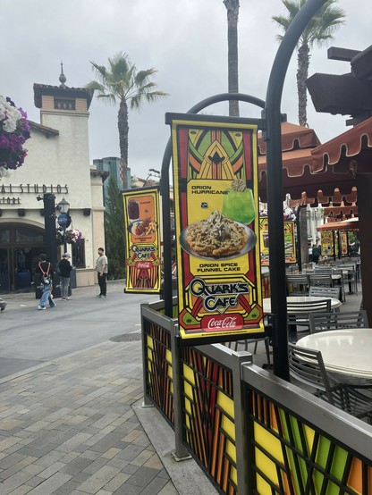 Photograph showing two brightly colored signs with the text Quark’s Cafe and different featured drinks and dishes themed to the Star Trek Universe.