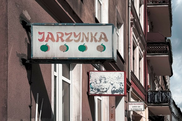 Bardzo stary szyld, przypuszczalnie zieleniaka. Widoczne rysunki warzyw i napis "Jarzynka".