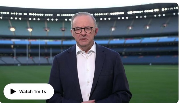 Anthony Albanese stands in an empty sports stadium, facing the camera. The background shows tiered seating with stadium lighting.