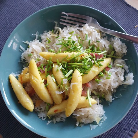 A dark green bowl with saurkraut topped with dried schupfnudeln (think giant german Gnocchi, but different) with bacon and scallions.